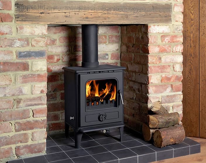 Black stove burning in a rustic stone inglenook